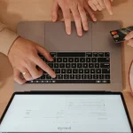 Два людини з ноутбуком і кредитною карткою під час онлайн-шопінгу, знято зверху.