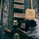 Вид зверху на робітника, який пакує мило у традиційній фабричній обстановці.