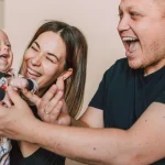 Щаслива сім'я з трьох людей, що сміються і спілкуються вдома, передаючи тепло і любов.