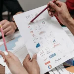 Група людей аналізує бізнес-звіти та графіки під час спільної зустрічі.