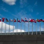 Ряд європейських прапорів, що колишуться на ясному блакитному небі, символізуючи єдність.