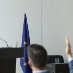 Жінка виступає на конференції, навколо слухачі, зосереджені на її виступі.