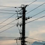 Силует ліній електропередач і опори на фоні яскравого заходу сонця