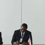 Два керівники підписують документ за столом із прапорами ЄС і США