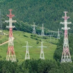 Високовольтні лінії передачі через зелені лісові пагорби, демонструючи енергетичну інфраструктуру.