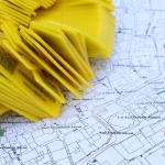 Стек жовтих маркерів з QR-кодами, розташованих на детальній карті для навігації та визначення місця
